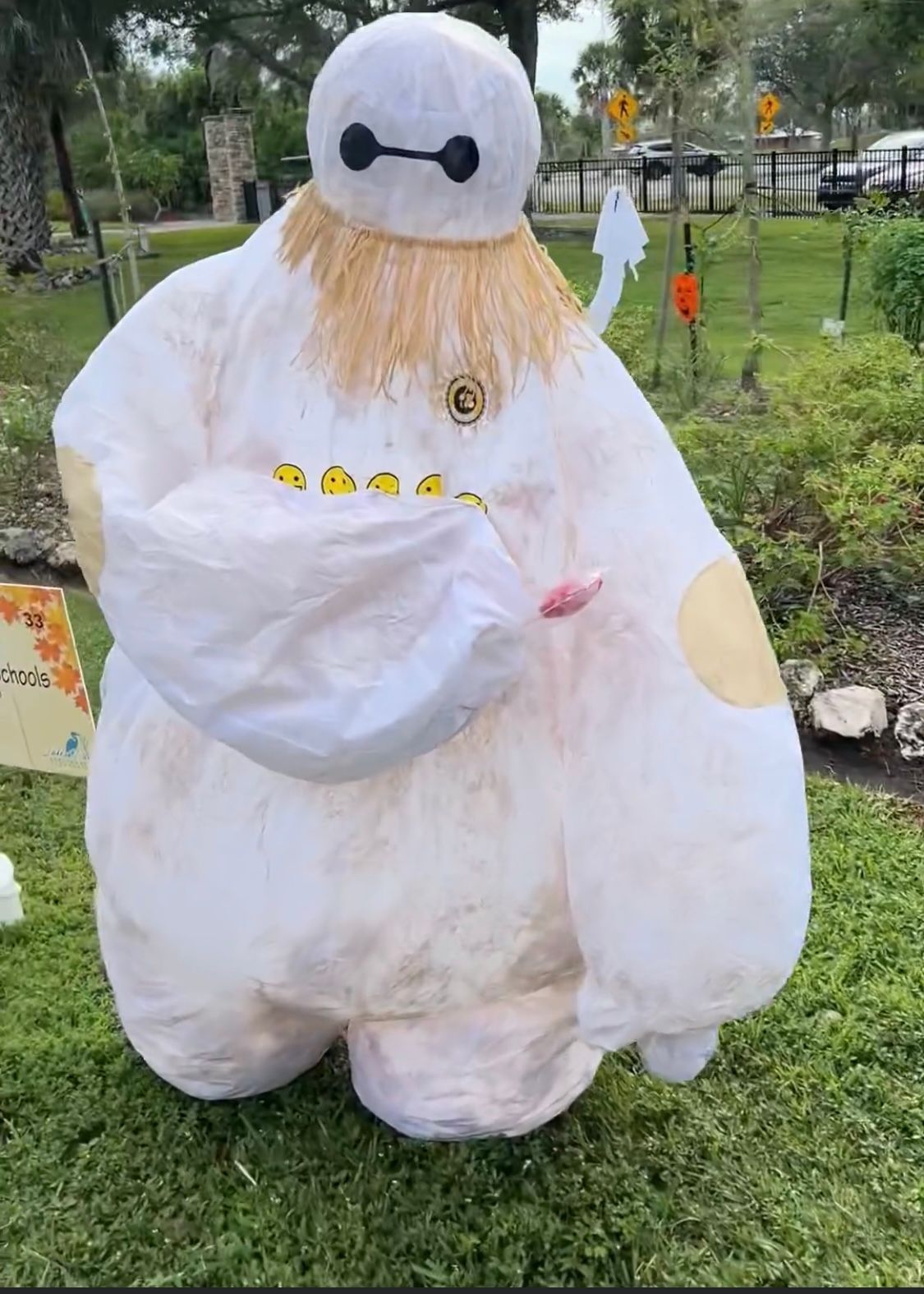 A scarecrow dressed as baymax from big hero 6 is standing in the grass.