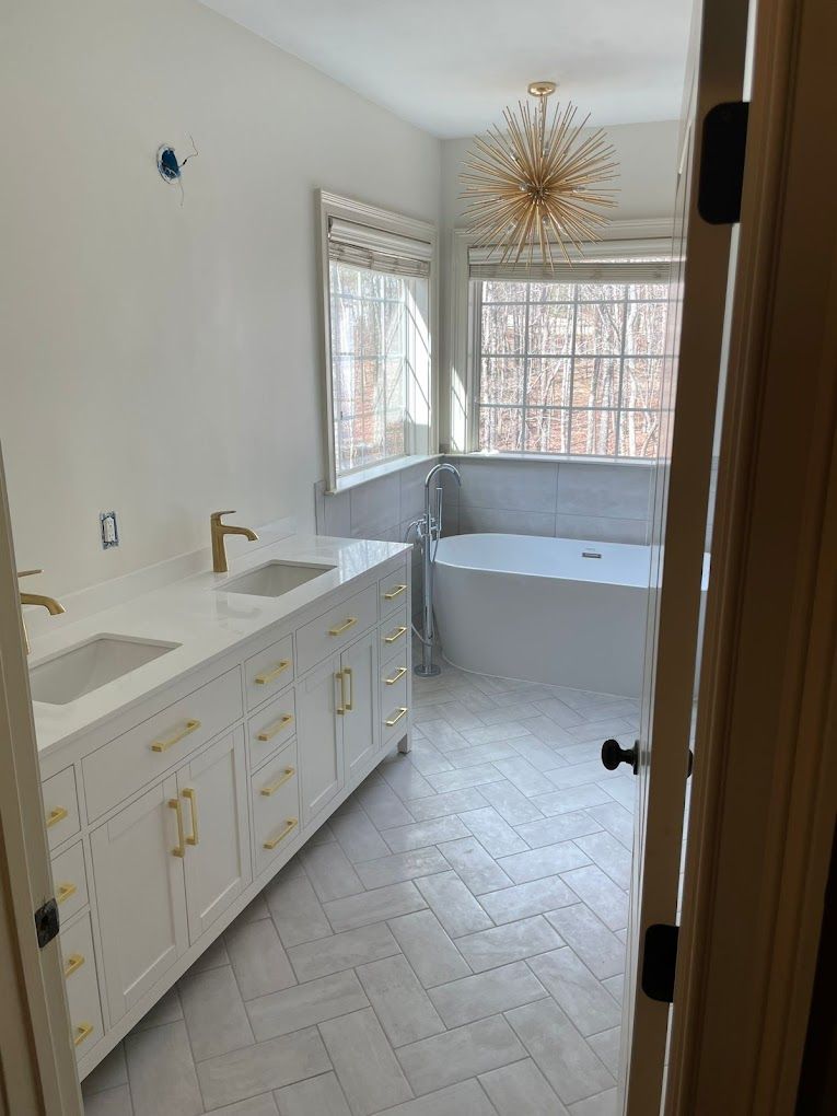 A bathroom with two sinks , a tub and a window.