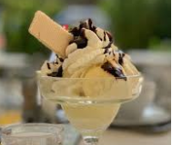 Ice cream sundae in a glass, with whipped cream, chocolate sauce, and a wafer.