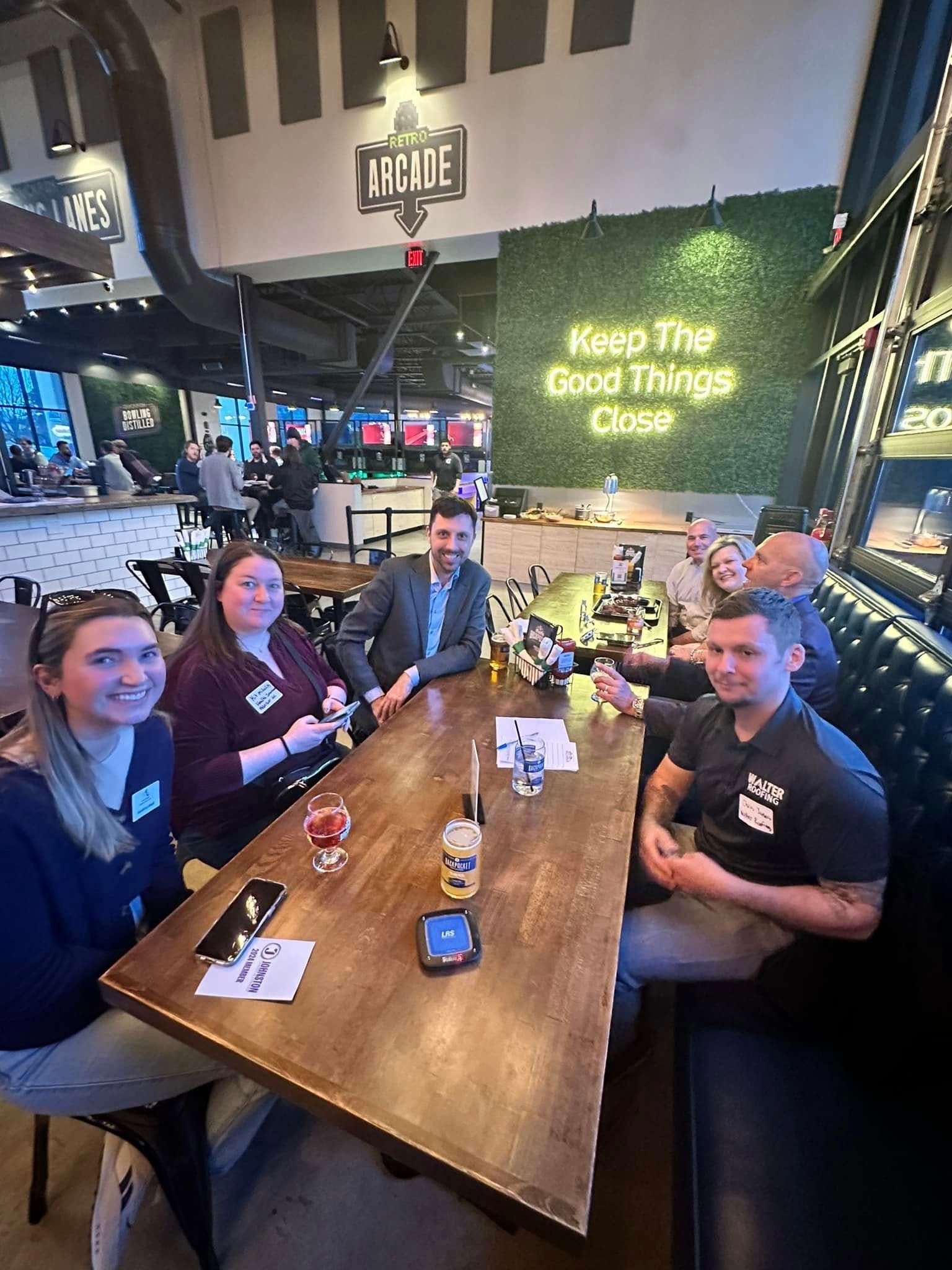 People seated around a table in an arcade. Drinks, phones, and name tags are visible. 