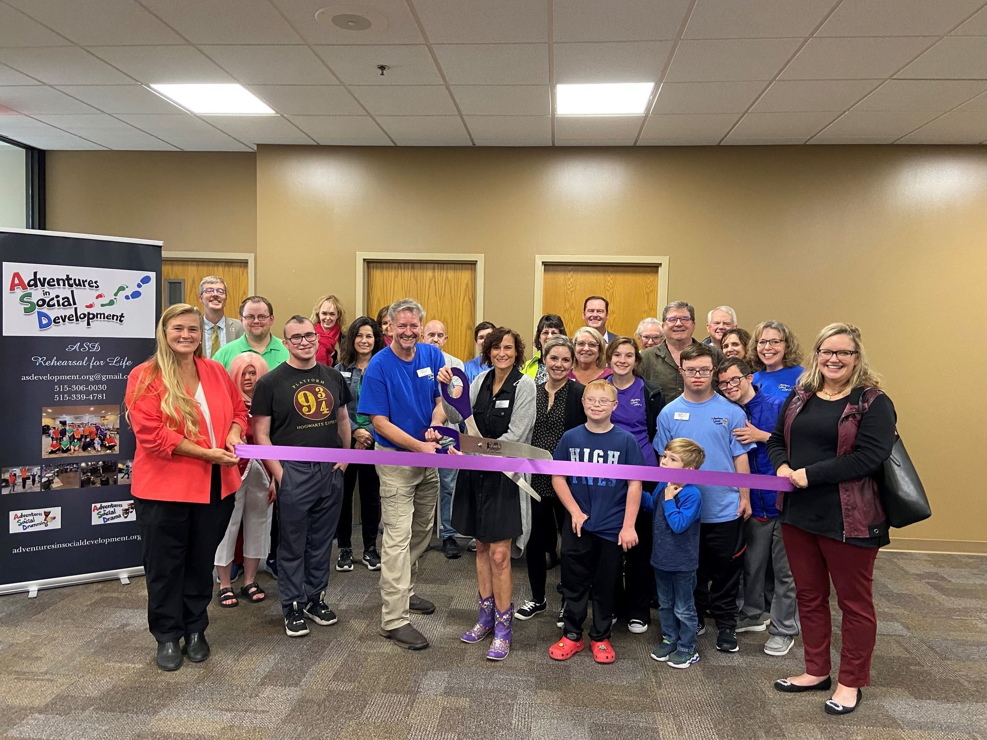 Group of people cutting a purple ribbon at an event. Banner with text on the left.