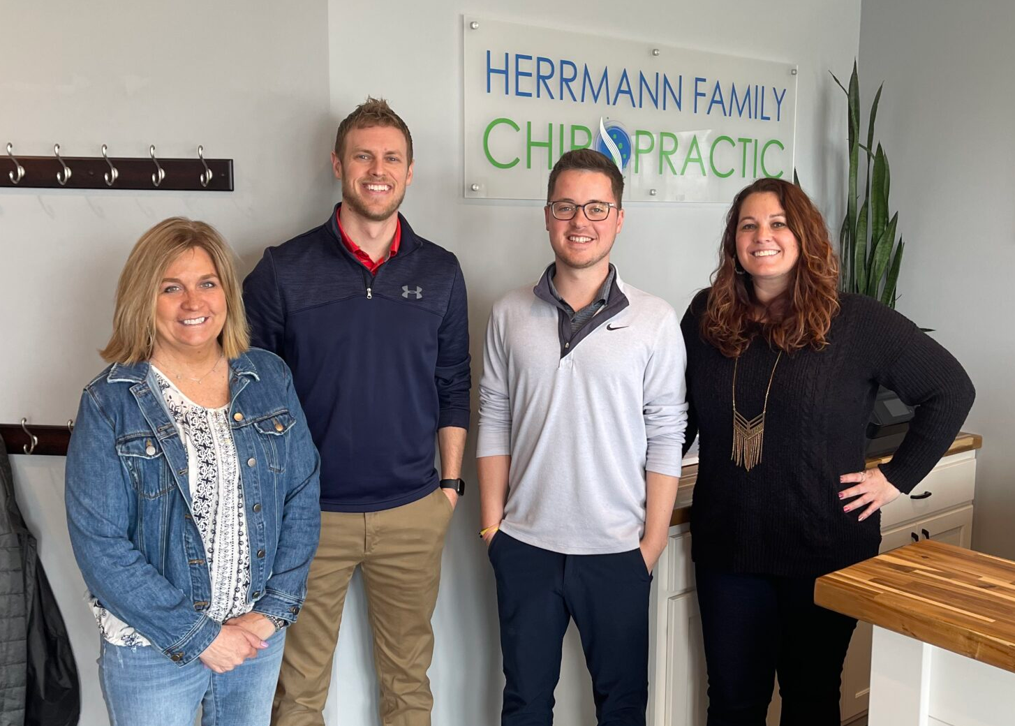 Four people posing in front of a chiropractic office sign.