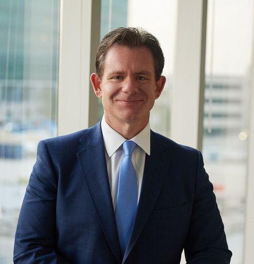 A man in a suit and tie is smiling in front of a window