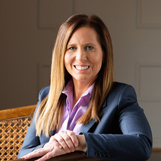 A man in a suit and tie is smiling in front of a window