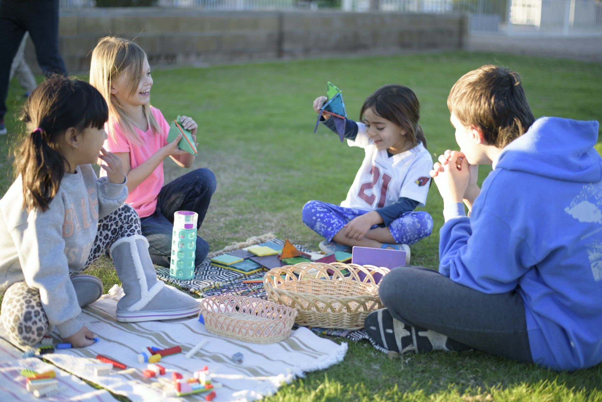 A group of children are sitting on the grass having a picnic.