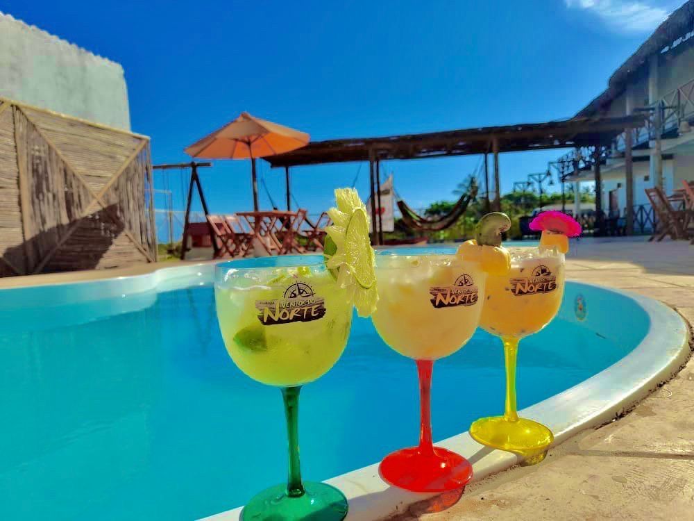 Três bebidas estão na borda de uma piscina.