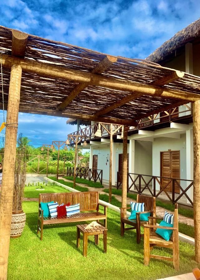 Um banco de madeira e cadeiras sob um telhado de palha