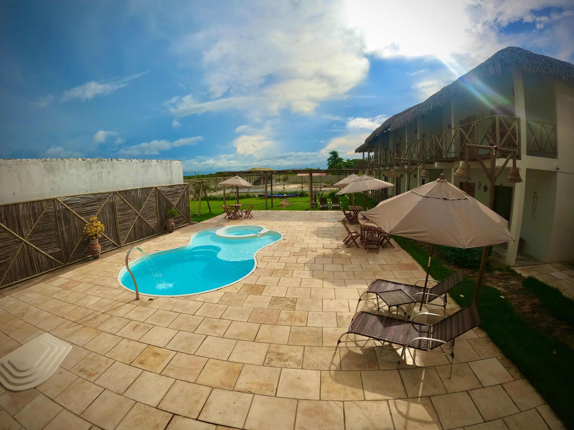 Uma grande piscina é cercada por mesas, cadeiras e guarda-sóis.