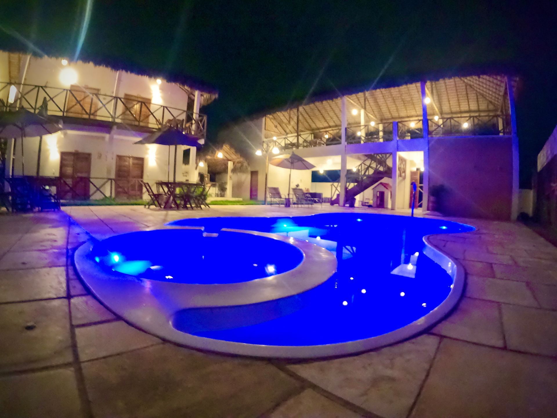 Uma grande piscina é iluminada à noite em frente a um prédio