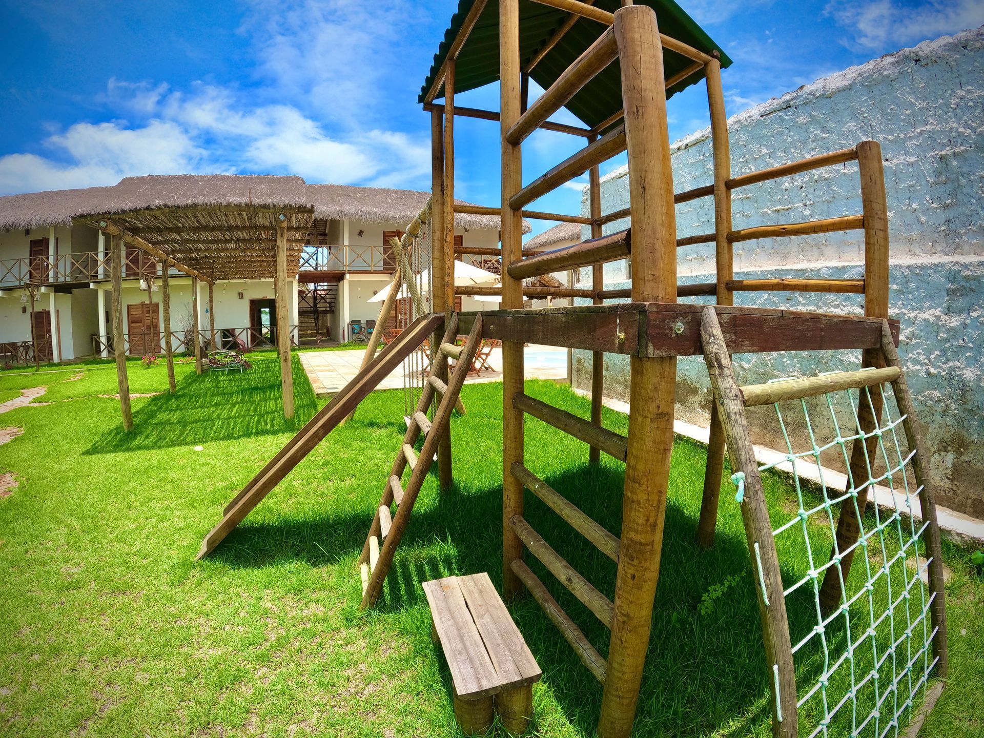 Um playground de madeira com escorregador e escadas em uma área gramada.