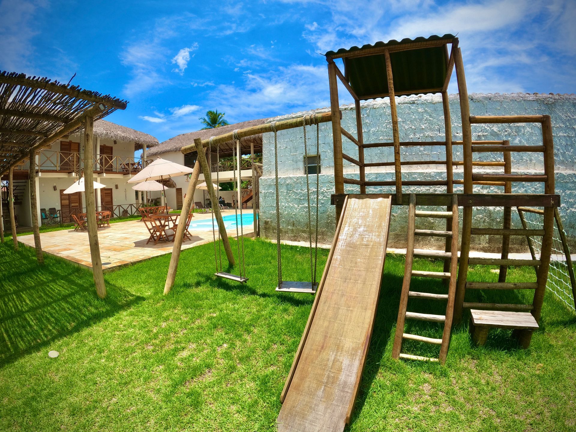 Um playground de madeira com escorregador, balanços e escadas