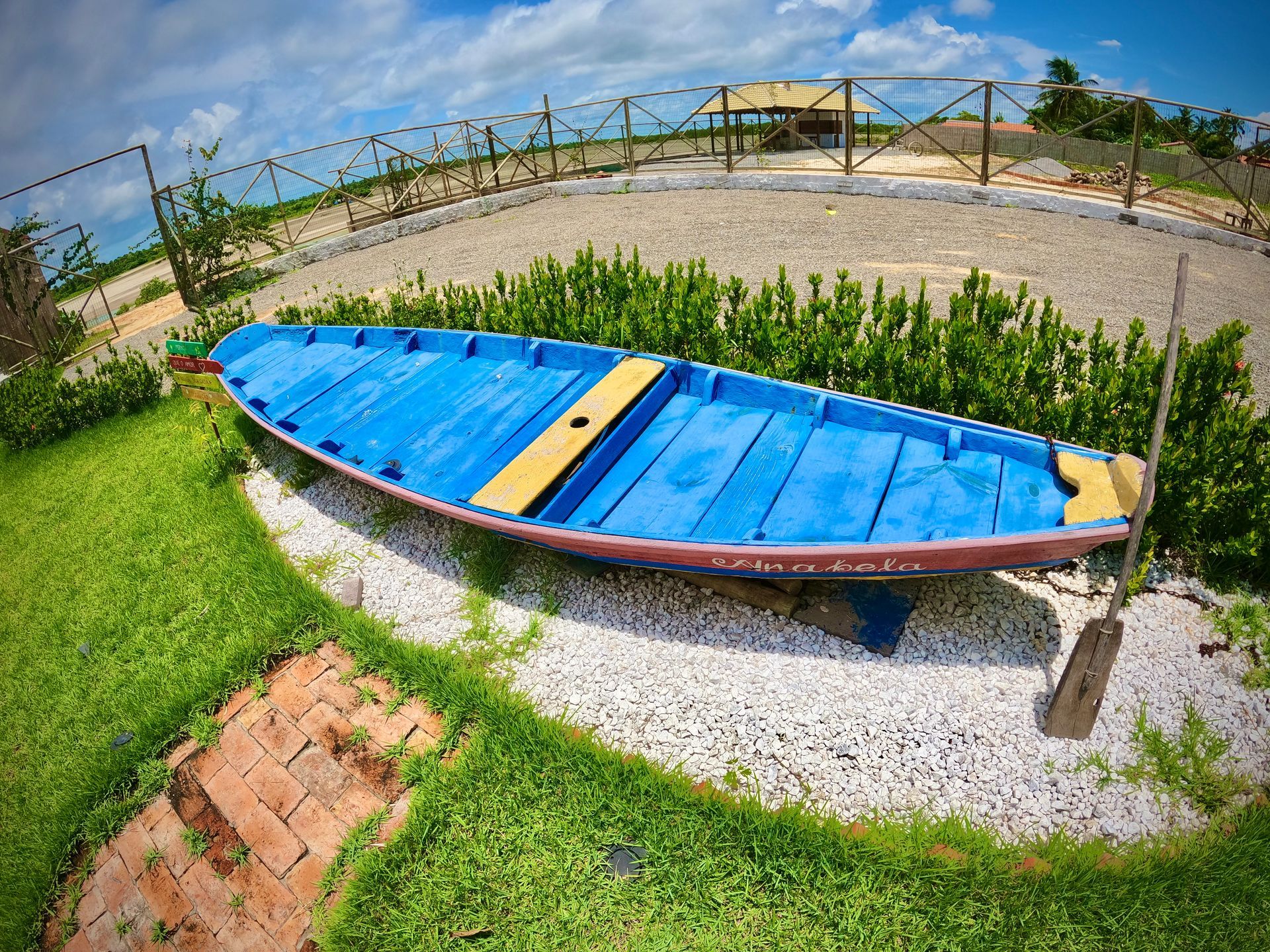 Um barco azul com um assento amarelo está sentado na grama.