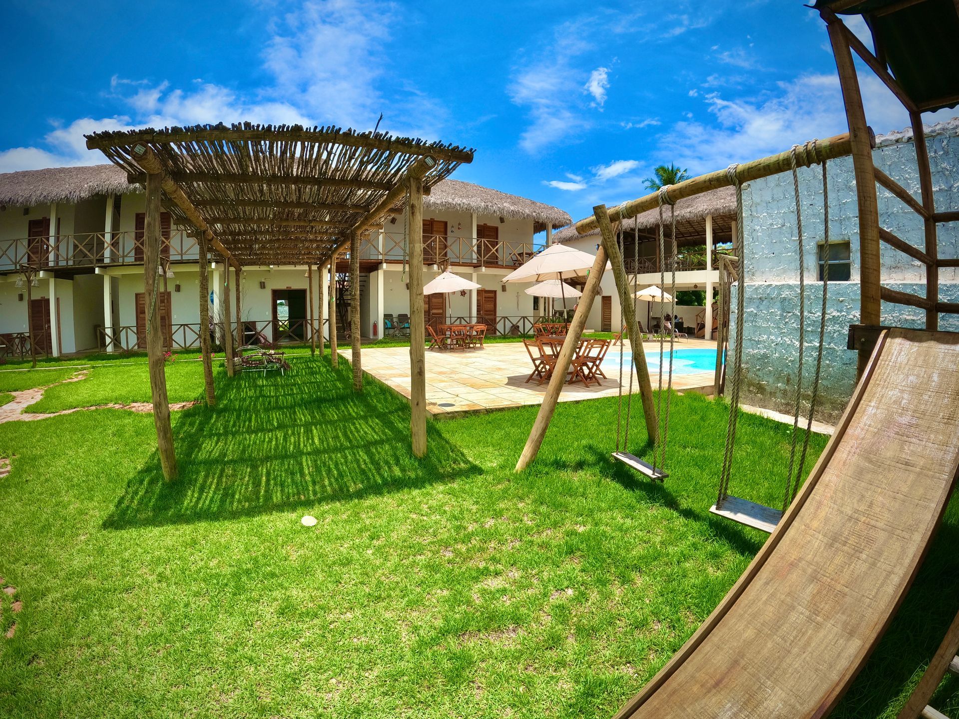 Um playground com escorregador e balanços em frente a um hotel.