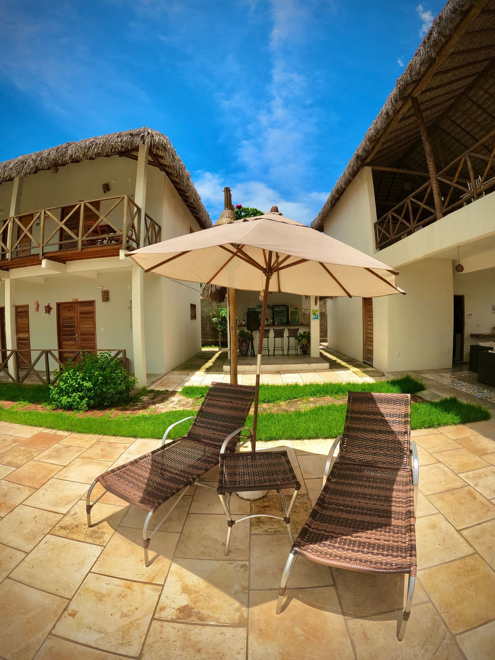 Um pátio com cadeiras e um guarda-sol em frente a um prédio