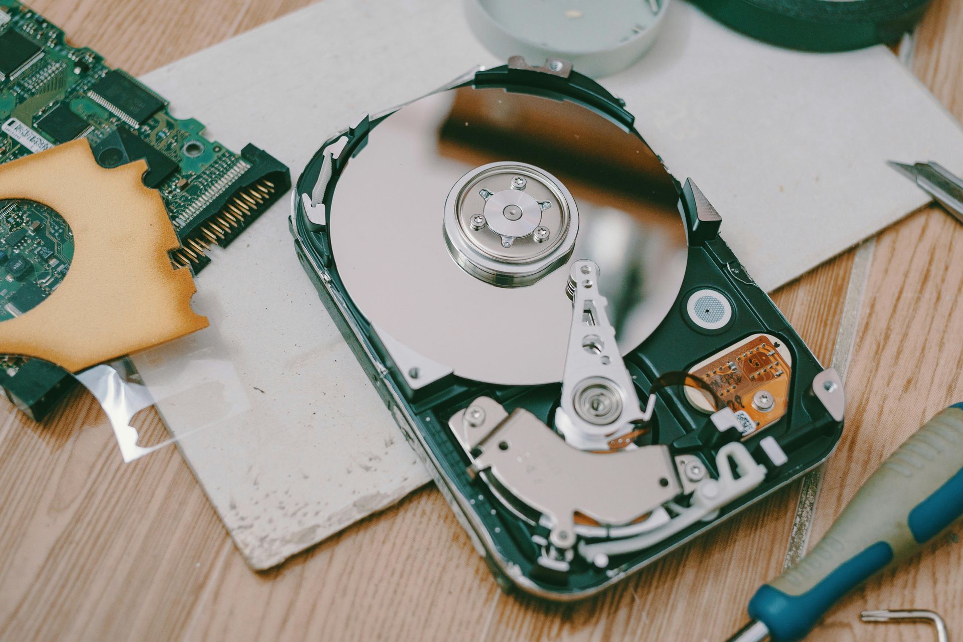 A hard drive is being repaired on a wooden table.