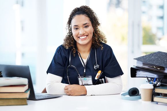 a nurse is sitting at a desk with a laptop and books