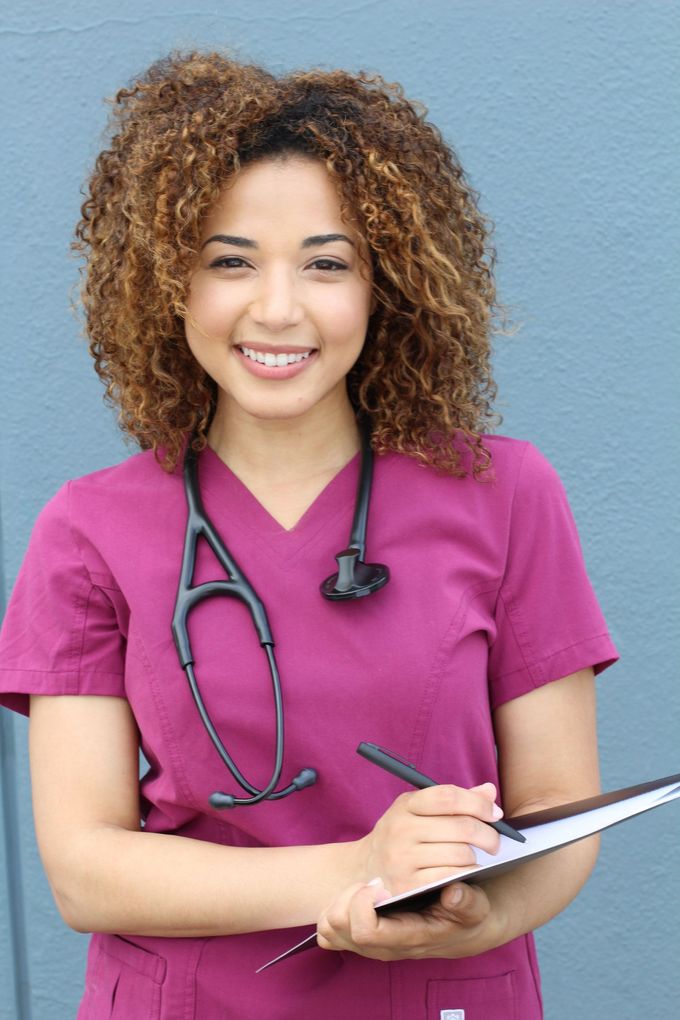 a nurse with a stethoscope around her neck is holding a clipboard and smiling