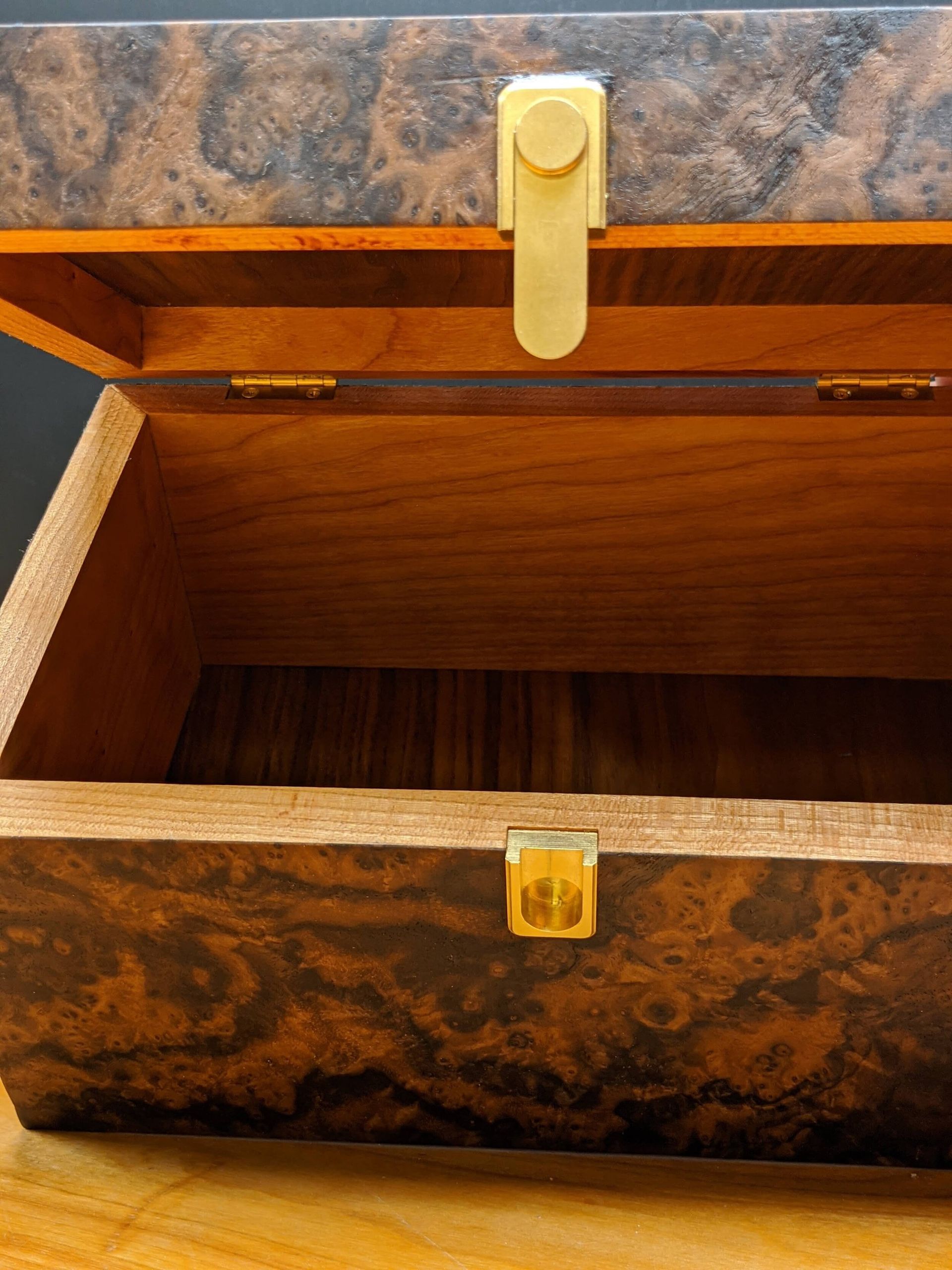 A wooden box with the lid open is sitting on a wooden table.