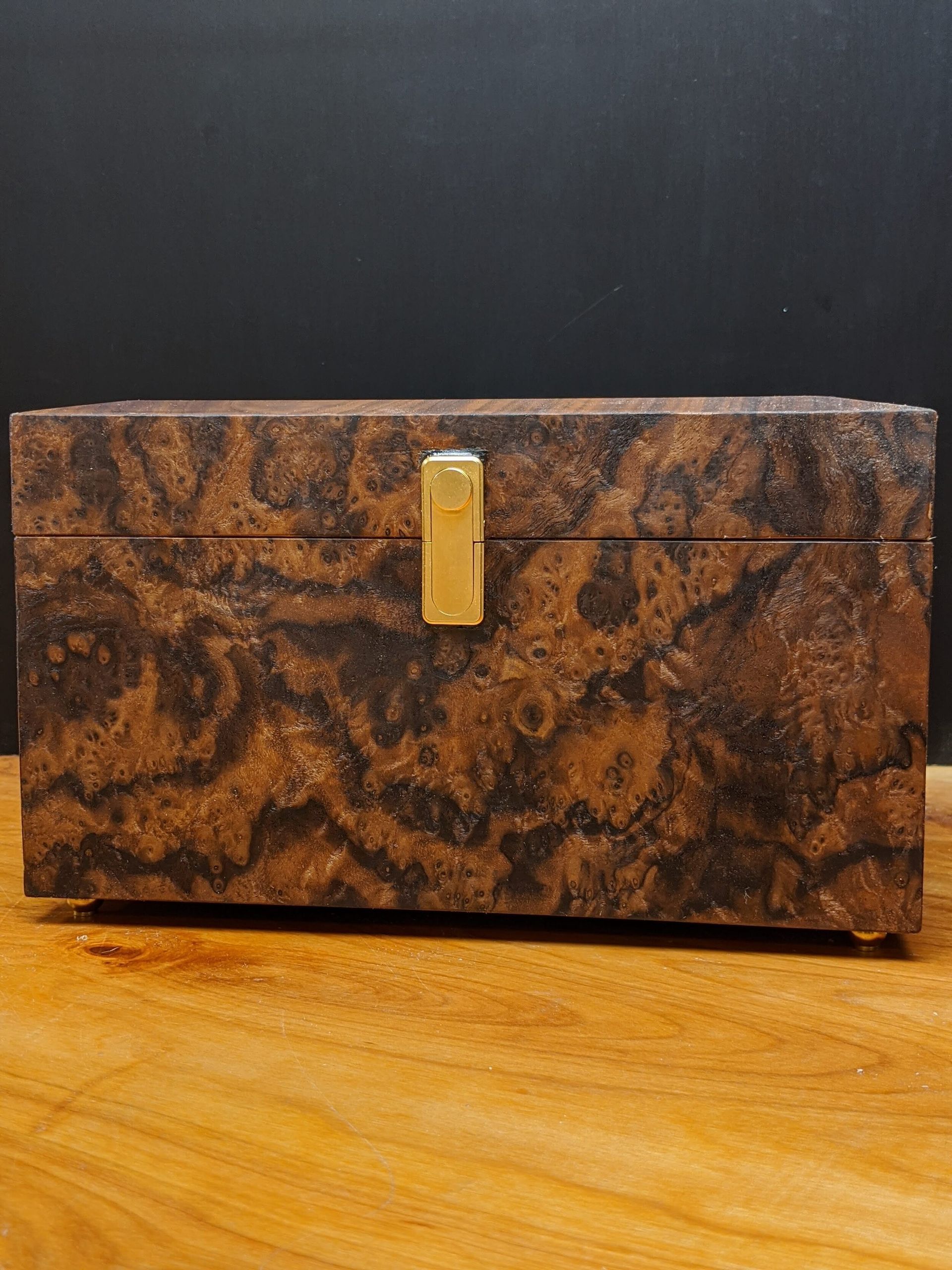 A brown box with a gold lock sits on a wooden table