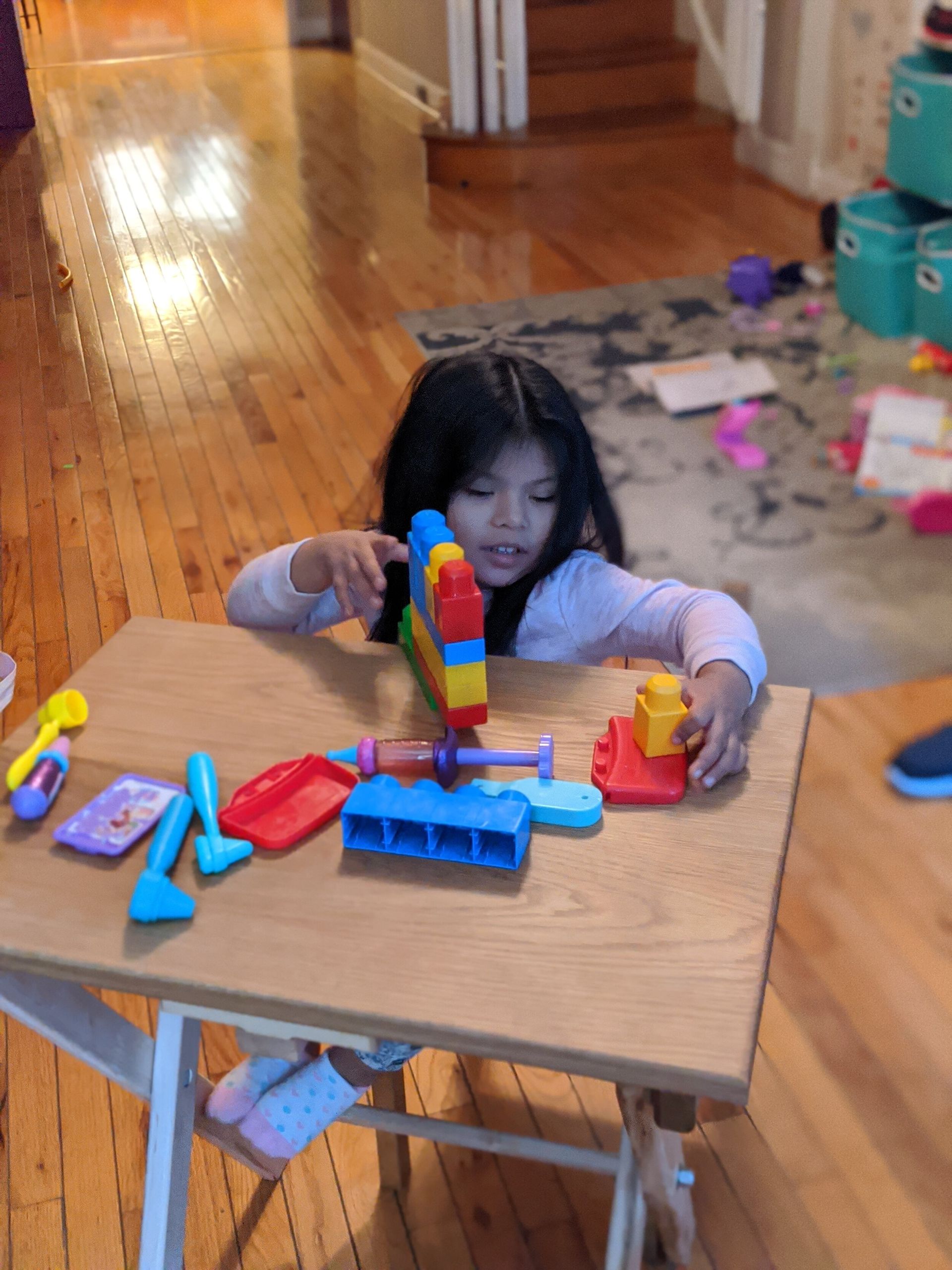 A little girl is sitting at a table playing with toys