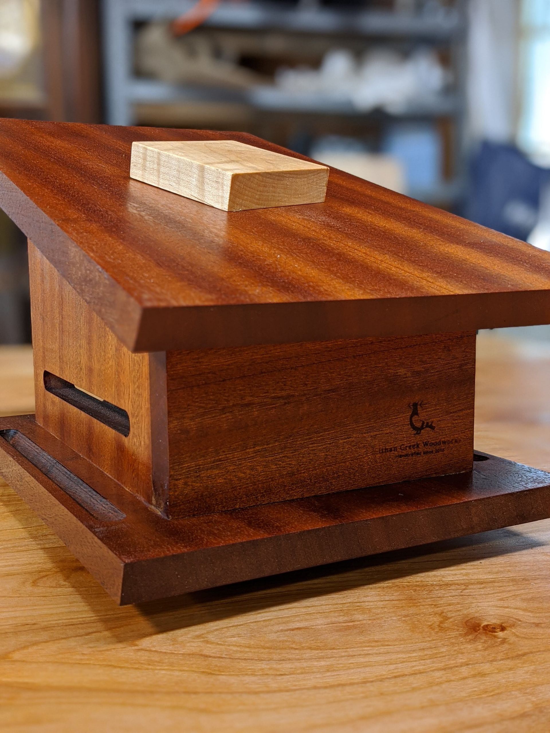 A wooden box with a piece of wood on top of it is sitting on a wooden table.