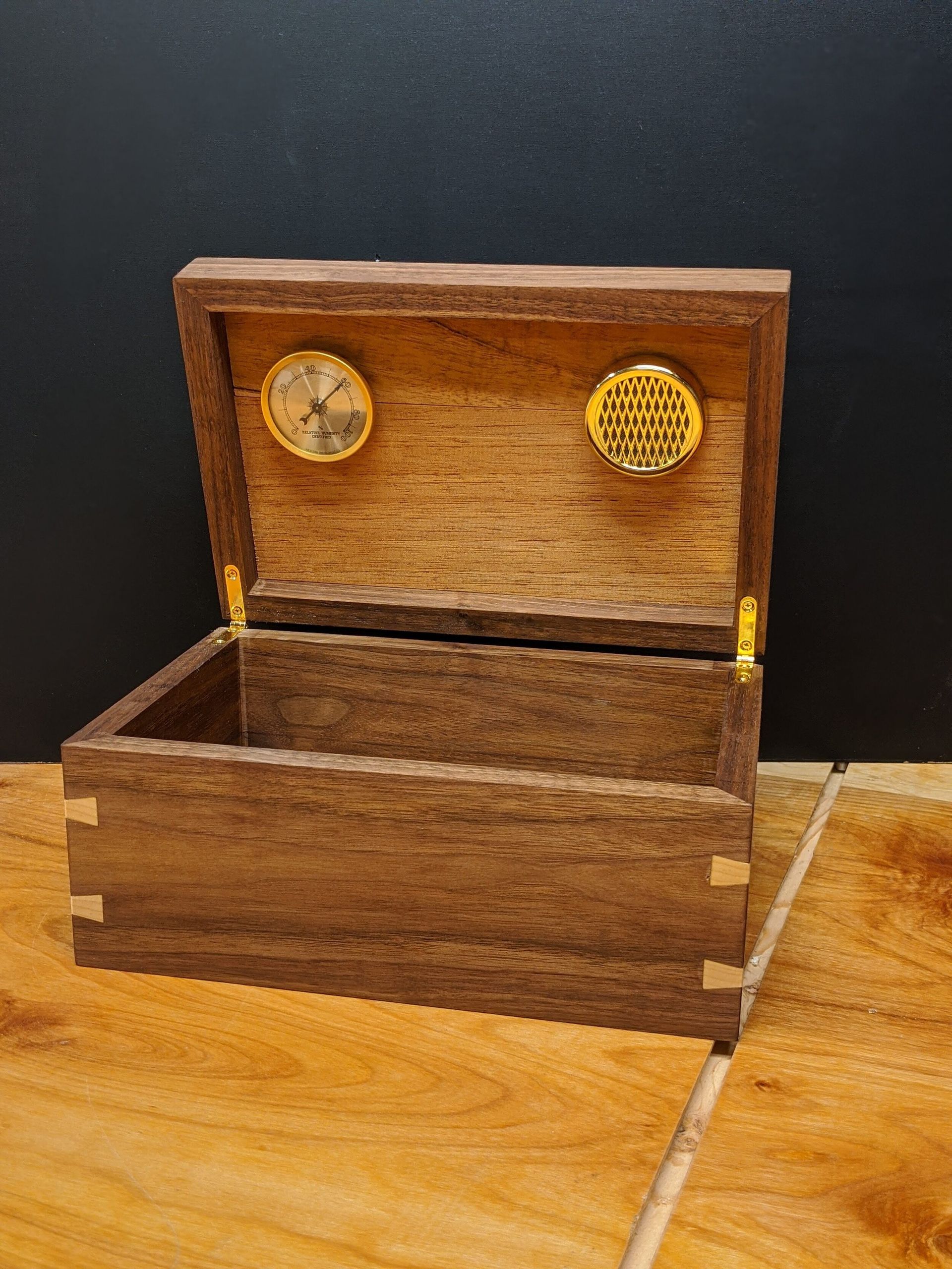 A wooden box with the lid open is sitting on a wooden table.