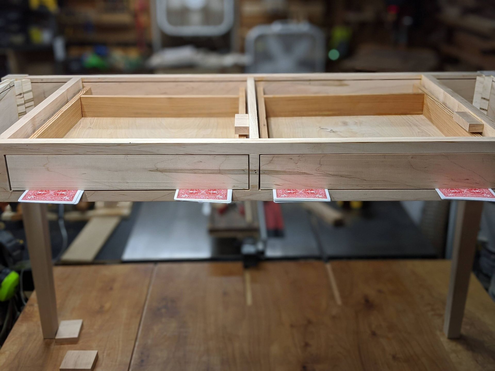 A wooden table with two drawers and playing cards on it