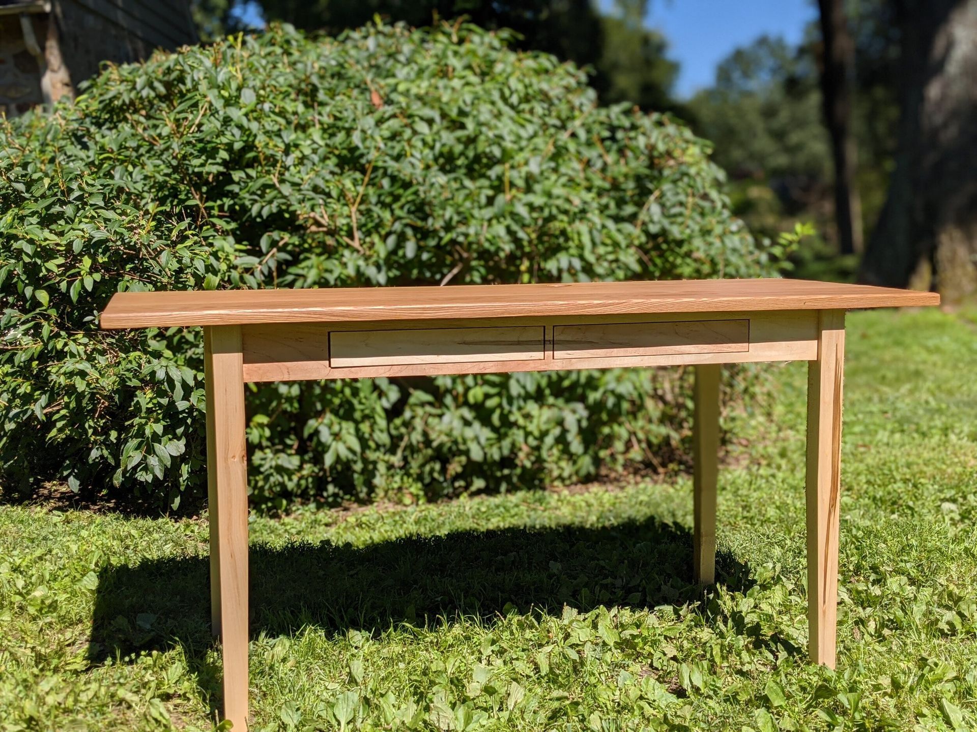 A wooden table is sitting on top of a lush green field.