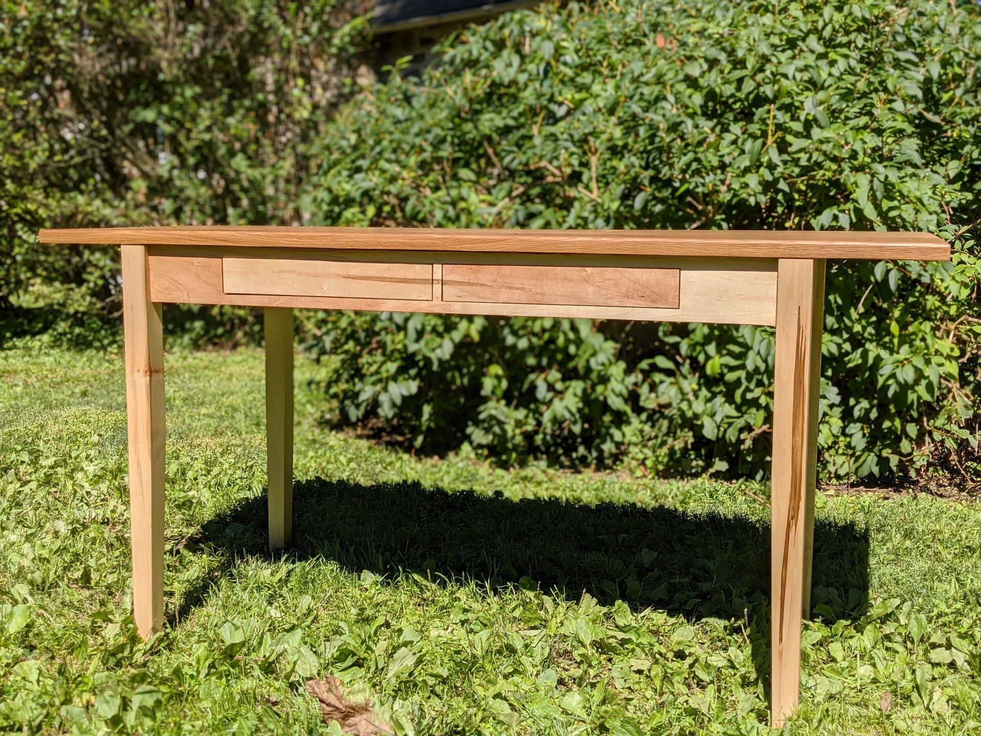 A wooden table is sitting on top of a lush green field.