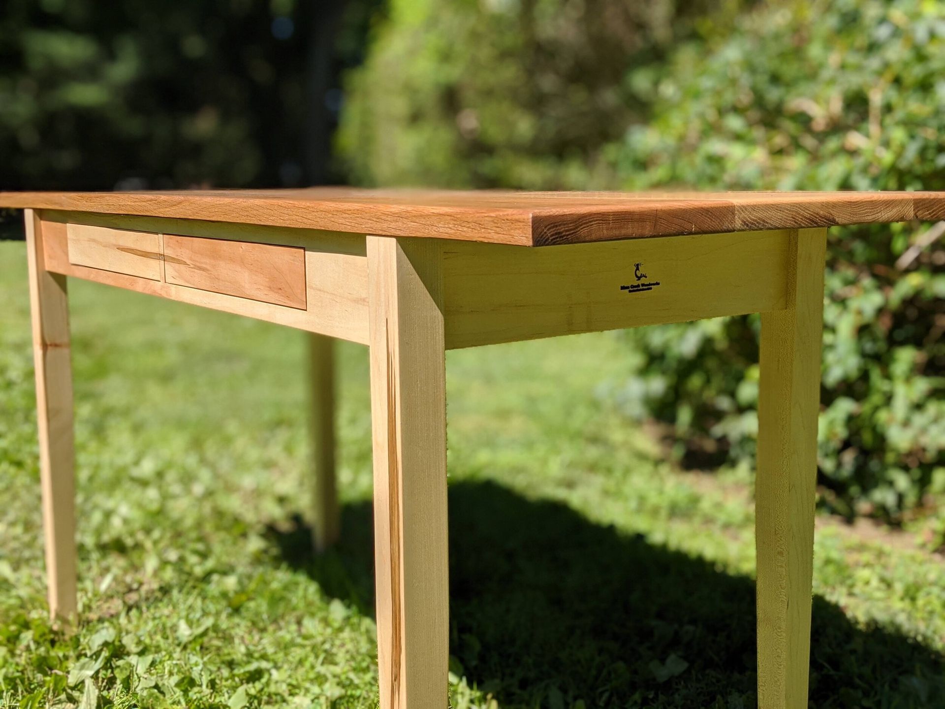 A wooden table is sitting on top of a lush green field.
