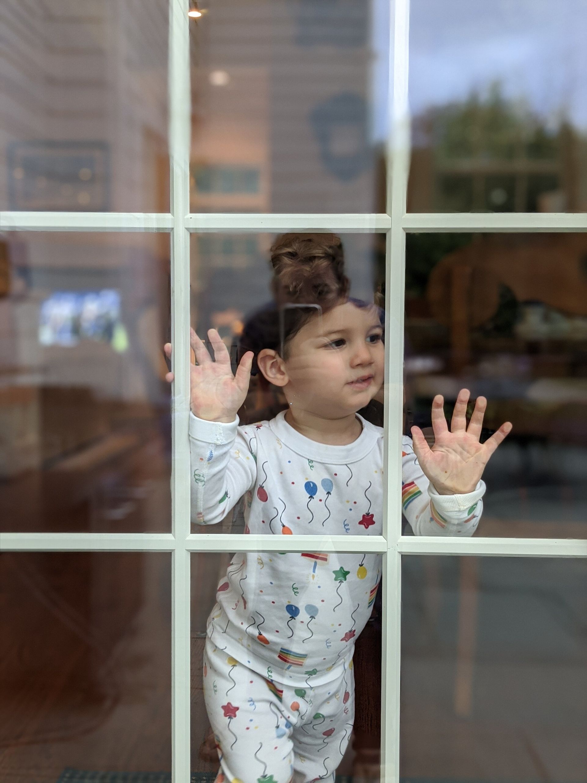 A little girl is looking out of a window.