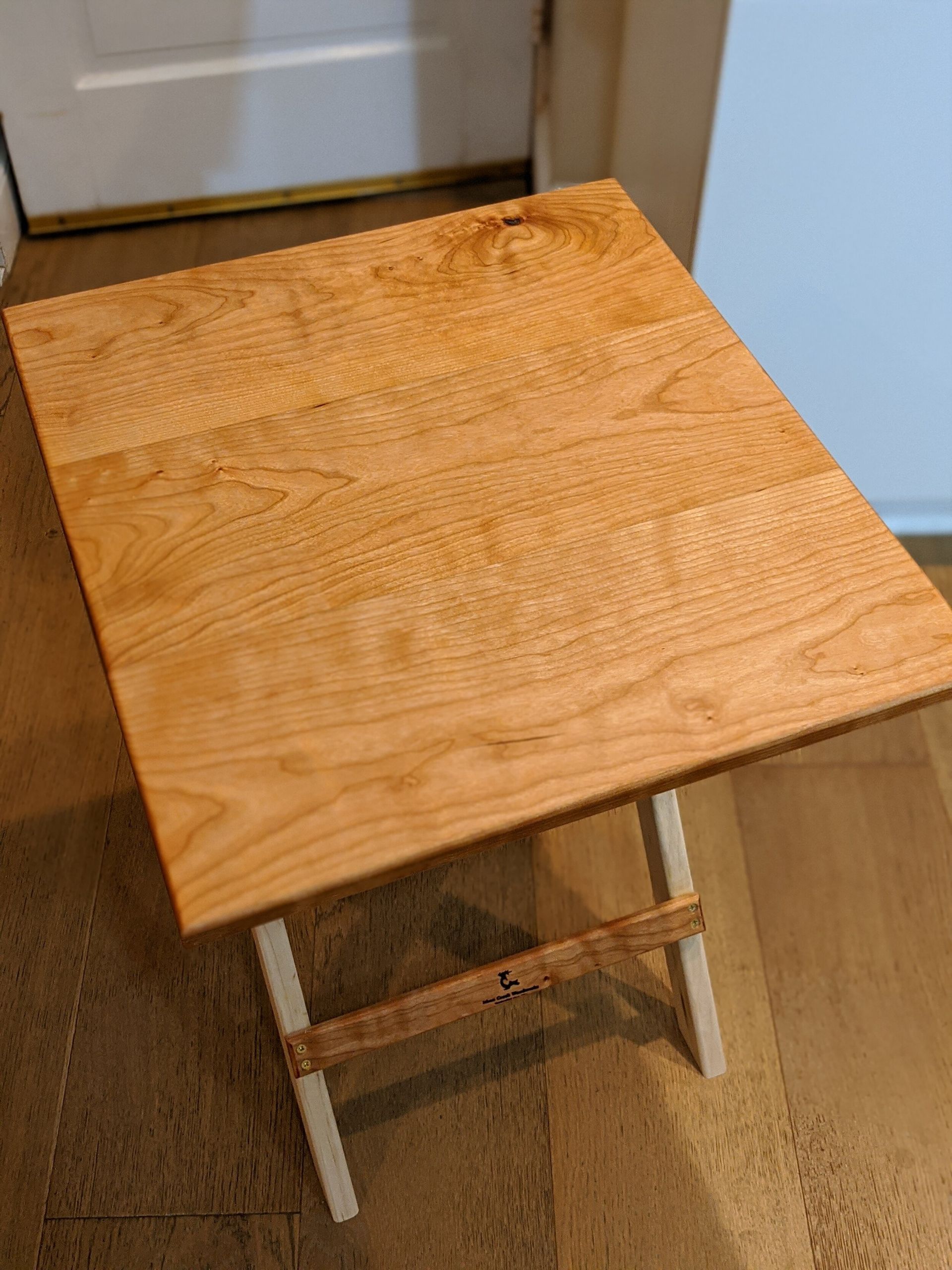 A small wooden table is sitting on a wooden floor next to a door.