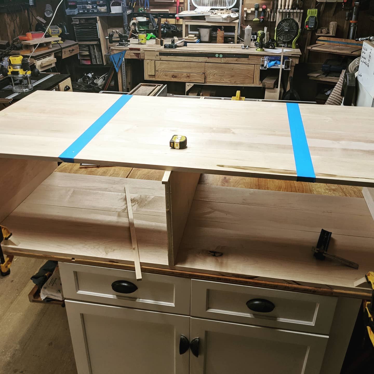 A wooden table with blue tape on it in a workshop