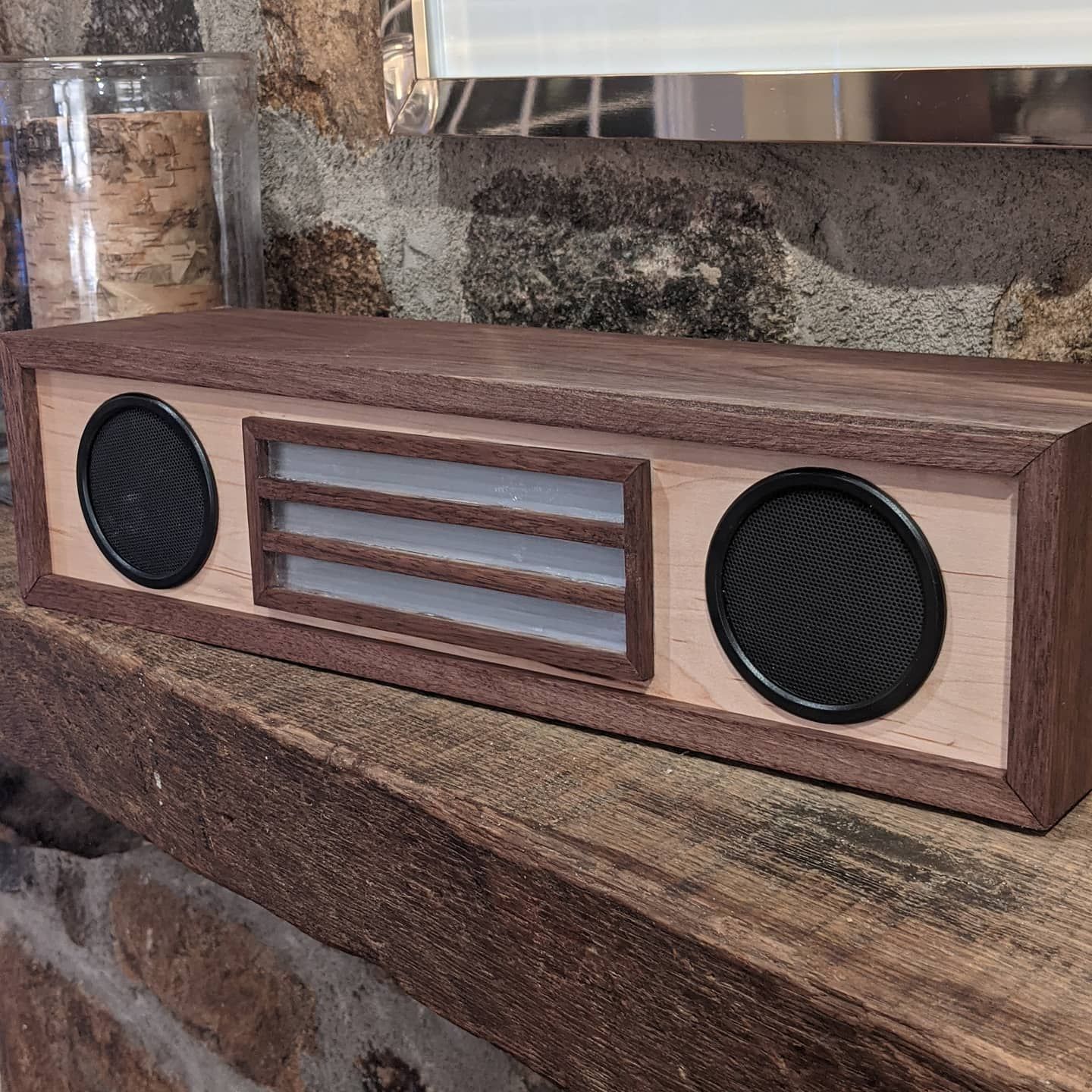 A wooden speaker is sitting on a wooden shelf.