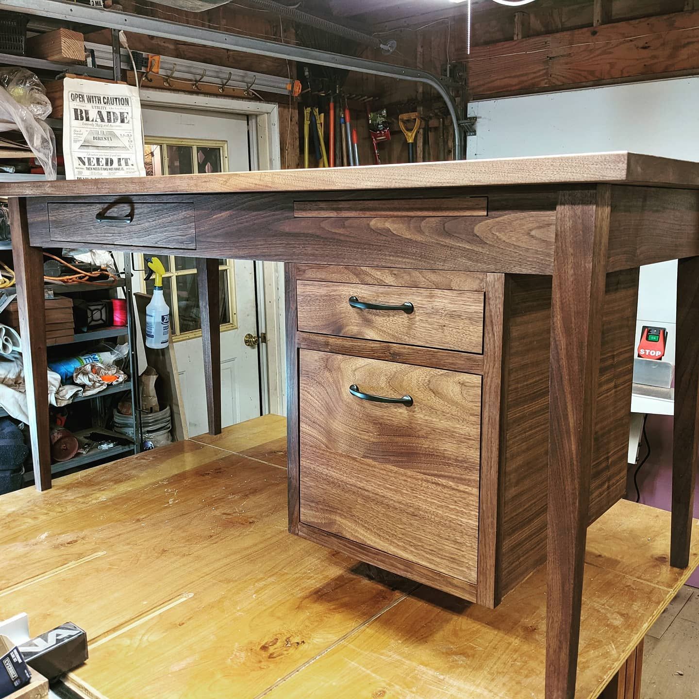 A wooden desk with drawers is sitting on top of a wooden table.