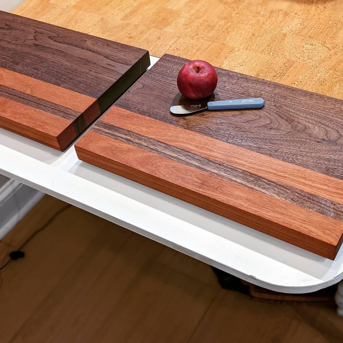 Two wooden chopping boards with apples and a small knife.