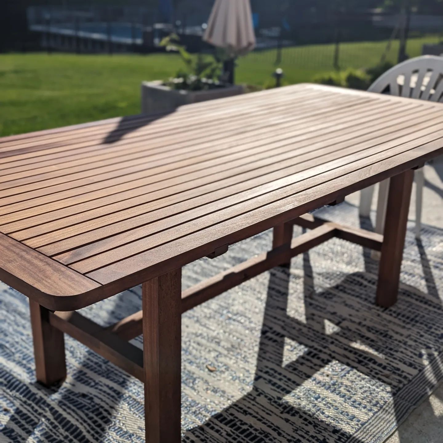 A wooden table is sitting on a rug on a patio