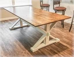 A wooden table with a white base is sitting on a wooden floor next to two chairs.