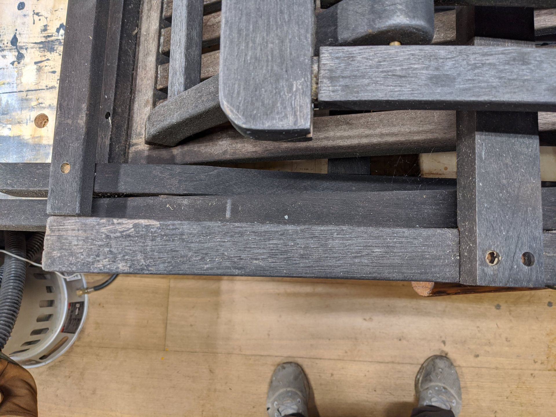 A person is standing next to a pile of wooden pallets.