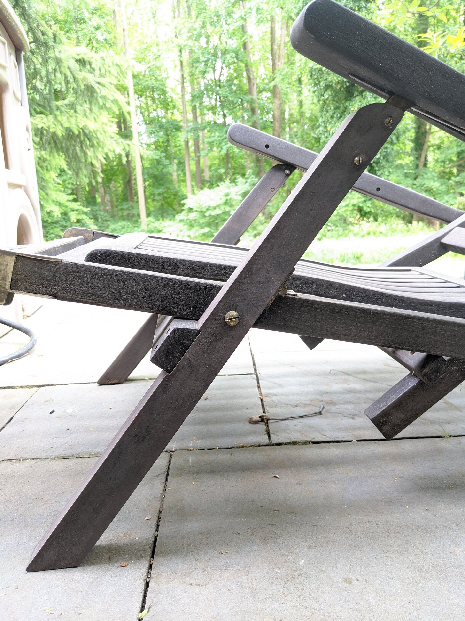 A wooden chair is sitting on a patio with trees in the background