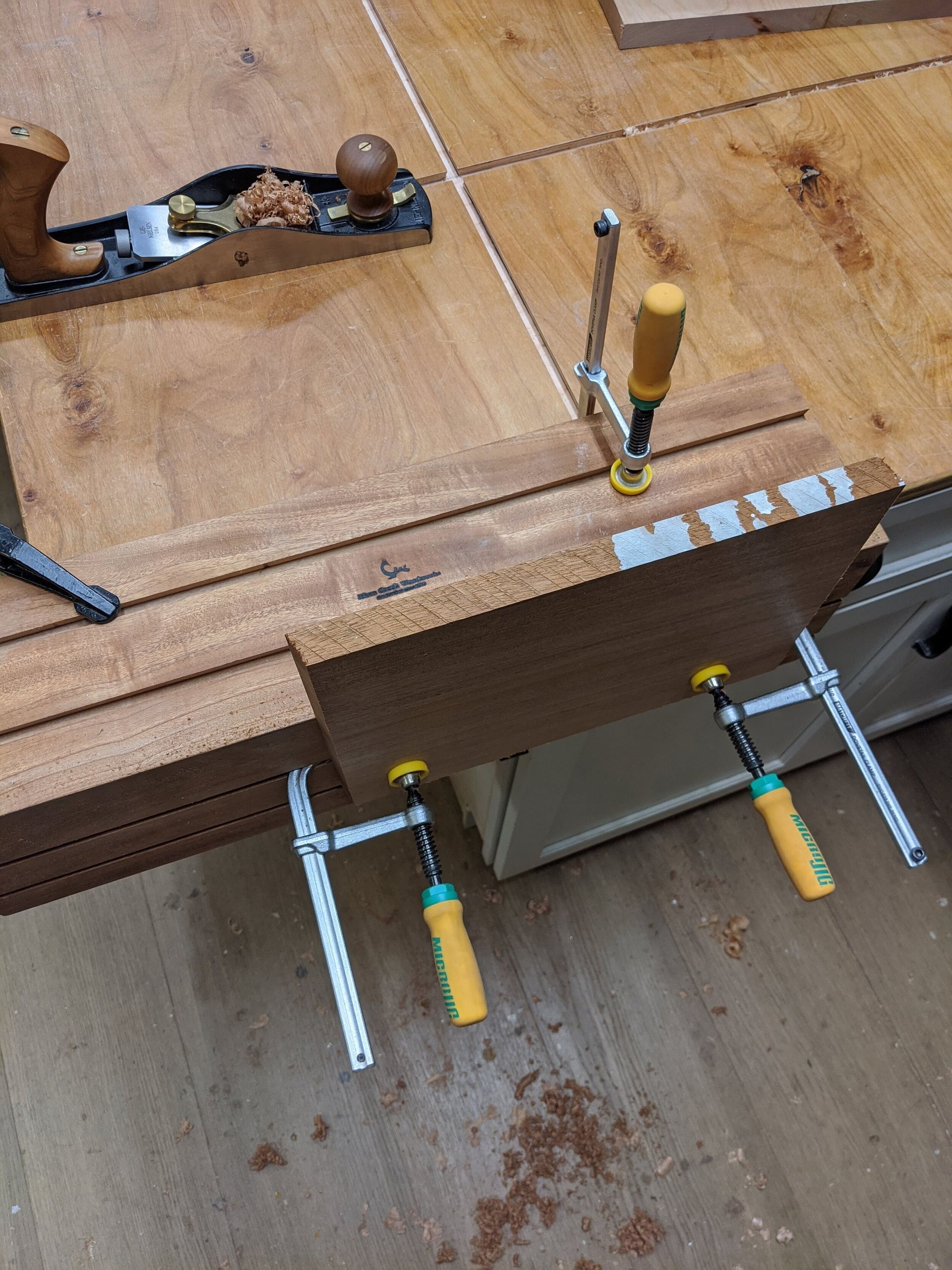 A wooden workbench with a plane and clamps on it