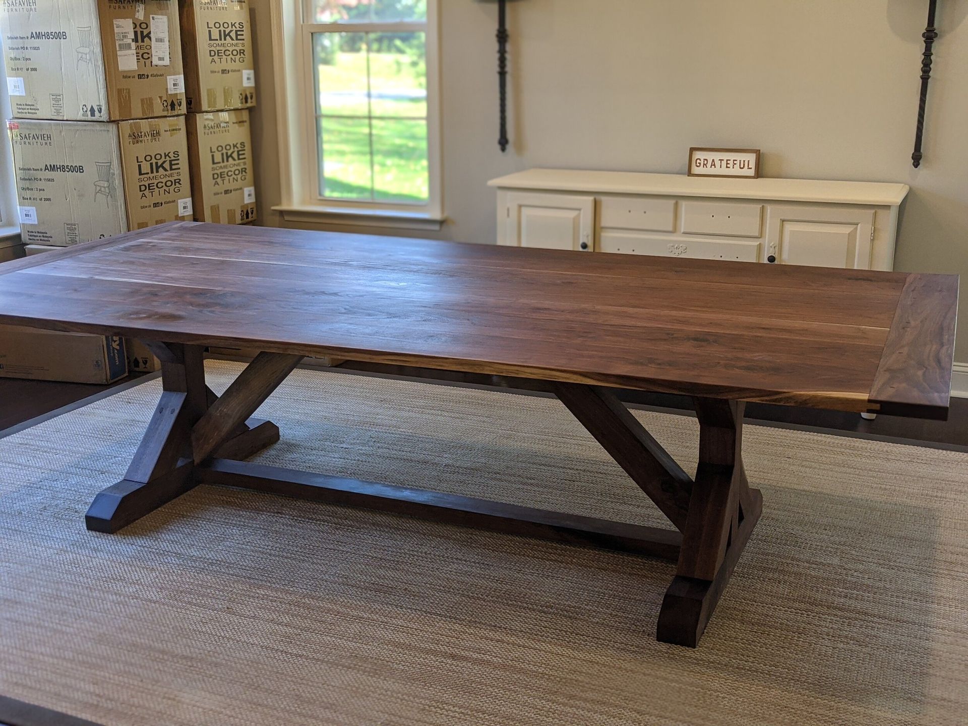 A large wooden table is sitting on a rug in a room.