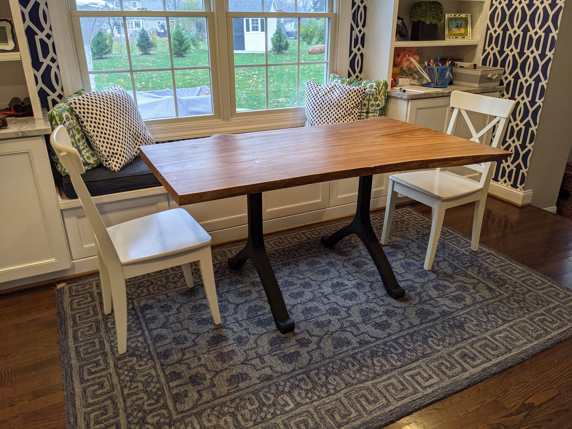A wooden table and chairs are sitting in front of a window in a living room.