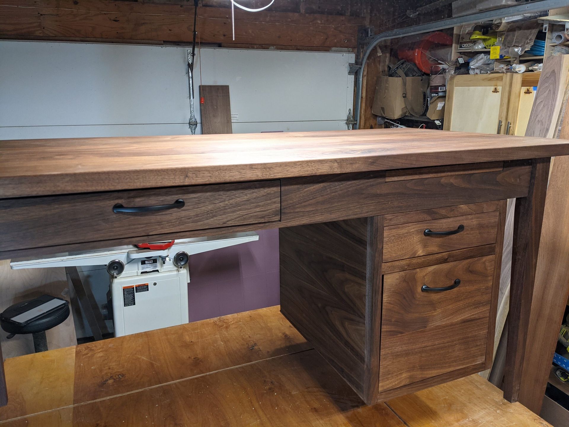 A wooden desk with drawers underneath it in a garage.