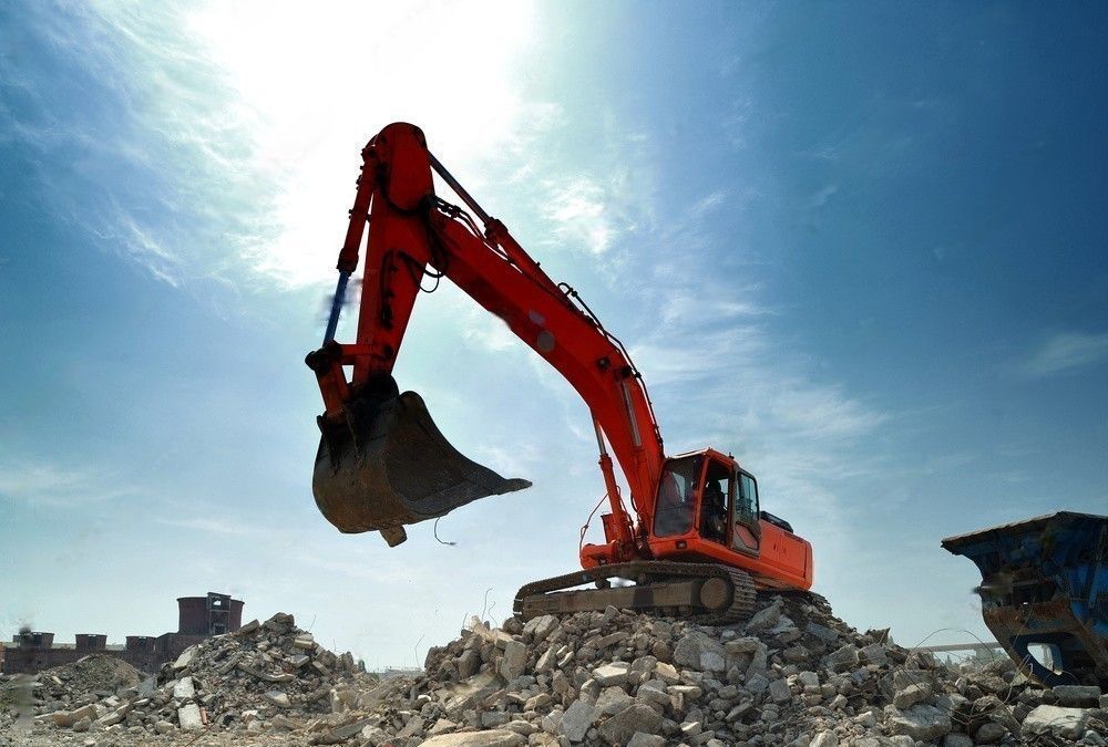 A large orange excavator is sitting on top of a pile of rocks.