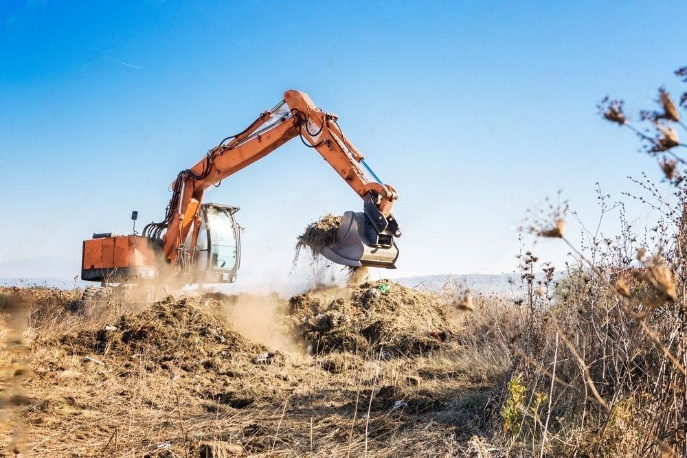 An excavator is digging a hole in the dirt in a field.