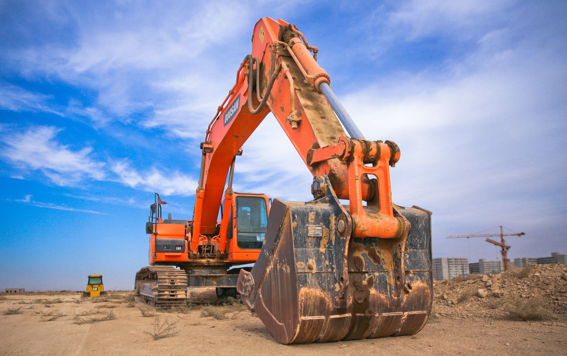 A large orange excavator is parked in the middle of a dirt field.