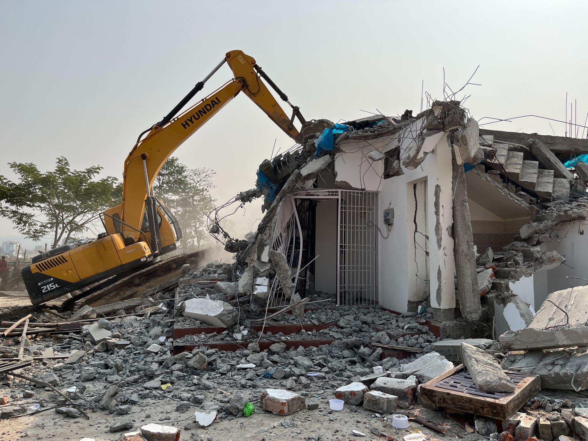 A yellow excavator is demolishing a building.