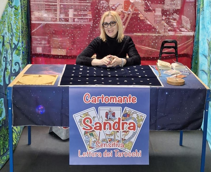 Una donna bionda è seduta a un tavolo con un cartello che recita