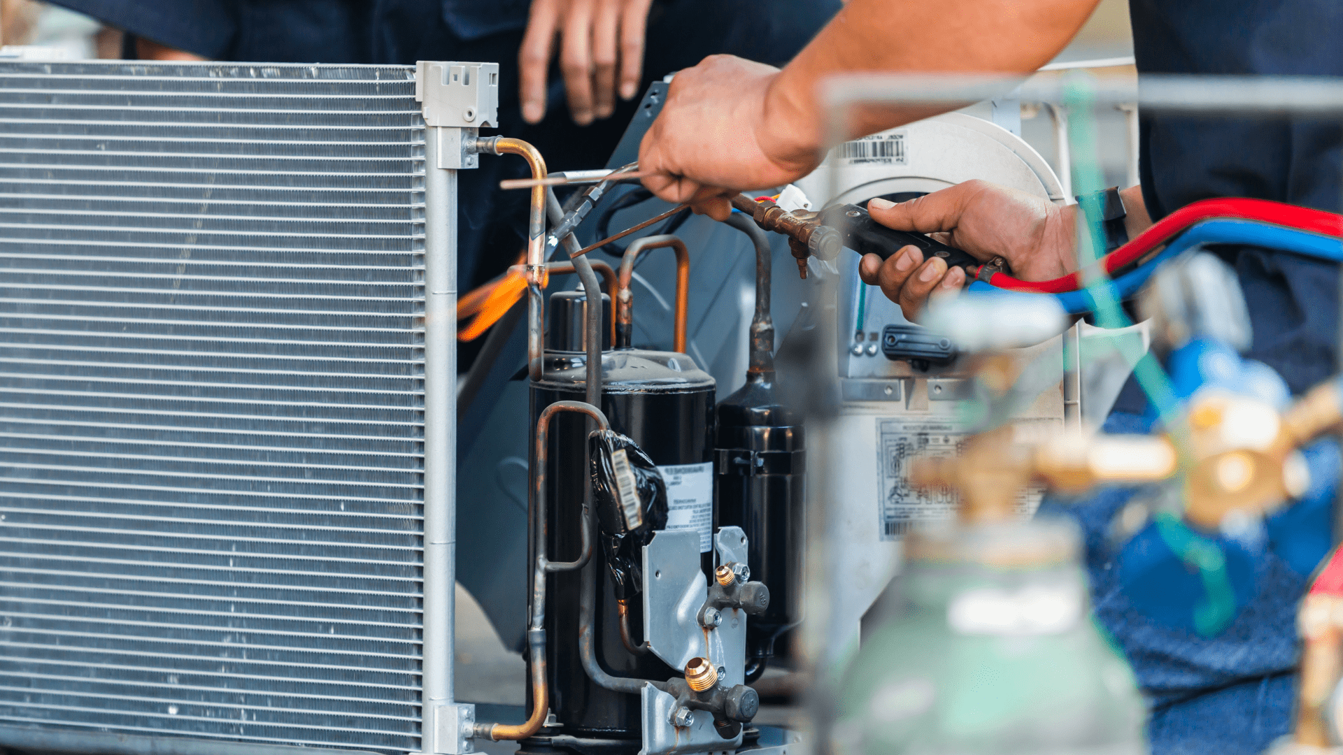 A man is working on an air conditioner with a wrench.